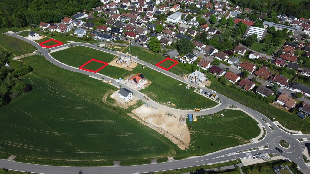 Drohnenaufnahme mit drei farblich markierten Bereichen, die Bauplätze darstellen. Die Markierungen wurden freihändig vorgenommen und dienen lediglich der groben Orientierung. Durch die Perspektive aus der Luft kann es zu Verzerrungen kommen; eine rechtlich verbindliche Aussage über Lage oder Größe ist damit nicht verbunden.